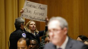 A police officer removes a woman protesting the Trans-Pacific Partnership (TPP). (