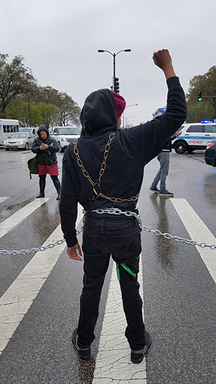 A protester awaiting arrest stands with a fist held high in defiance. (Photo: Kelly Hayes)