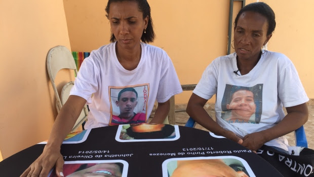 Ana Oliveira and Fatima Pinhos look at pictures of their sons, both killed by police. 
