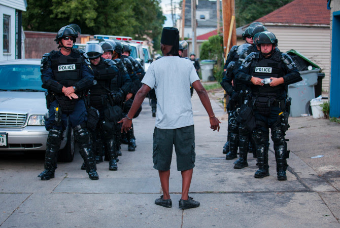 A man talks to police in riot gear as they wait in an alley after a second night of clashes between protesters and police Aug. 15, 2016, in Milwaukee.