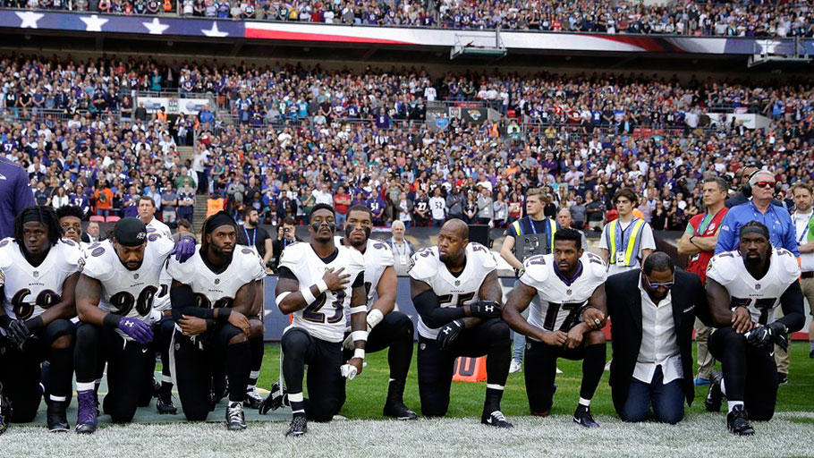 Baltimore Ravens players, including former player Ray Lewis, second from right, kneel down during the playing of the U.S. national anthem before an NFL football game against the Jacksonville Jaguars at Wembley Stadium in London, Sunday Sept. 24, 2017.