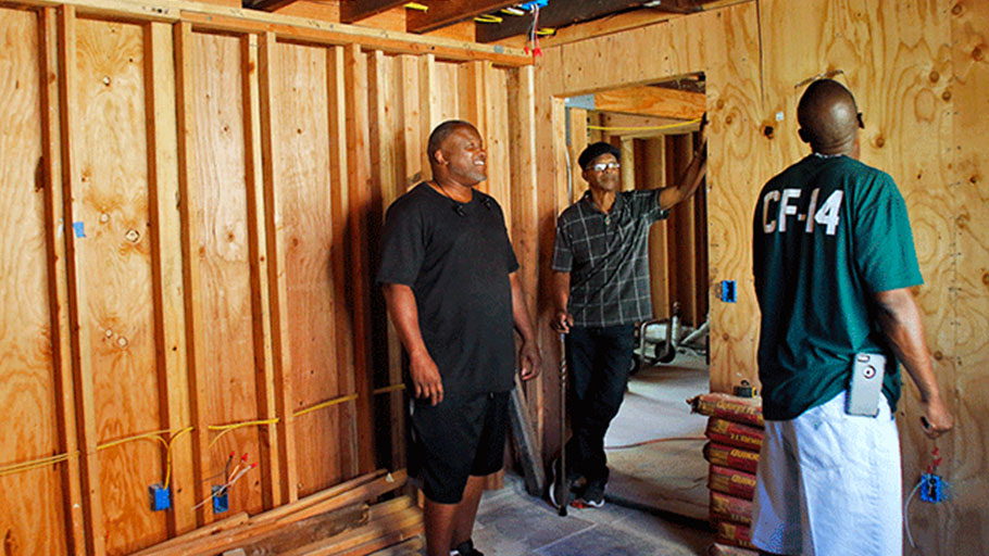 From left, Troy Williams, Watani Stiner, and Salin Johnson take a look around at their former garage, which is currently being converted to a downstairs unit with additional bedroom and office space to accommodate future residents of Sister Water.