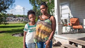 Tami Thomas-Pinkney with her daughter Trinity Handy on their front lawn in Port Arthur, Texas, across from one of the city's temporary dumpsites. (Photo: Julie Dermansky)