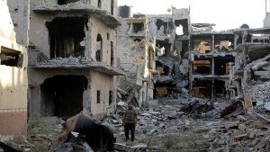 A man stands next to destroyed and damaged buildings in Sabri, a central Benghazi district, Libya