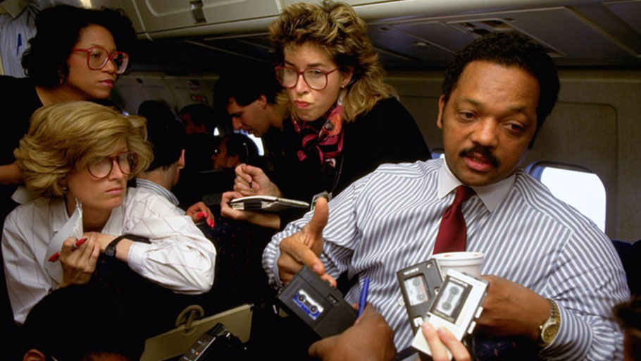 The Rev. Jesse Jackson speaks with reporters aboard a plane during a 1988 campaign stop in Ohio.
