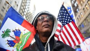 Protestor Pierre Gabriel from Haiti carries flags during a march on Martin Luther King Jr. Day in Times Square, called Rally Against Racism: Stand Up for Haiti and Africa in New York January 15, 2018.