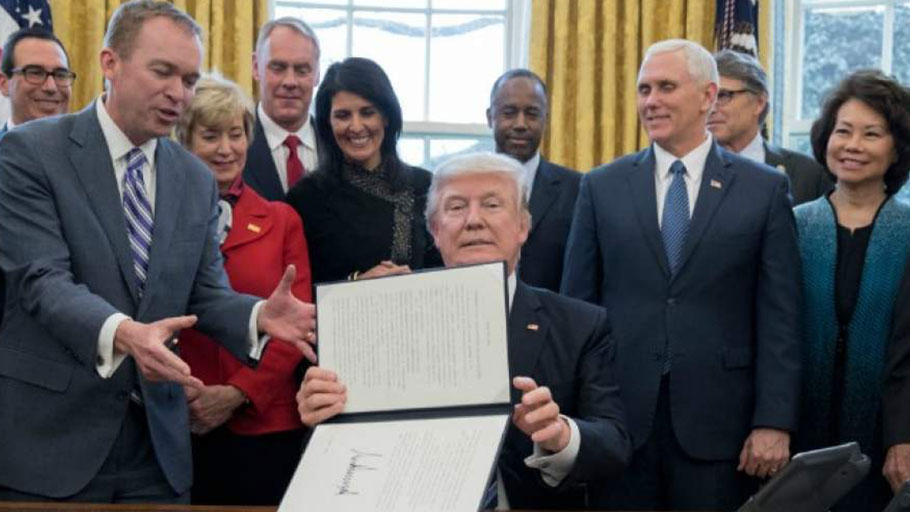 President Donald Trump shows an executive order entitled, 'Comprehensive Plan for Reorganizing the Executive Branch', after signing it beside members of his Cabinet in the Oval Office of the White House March 13, 2017 in Washington, D.C.