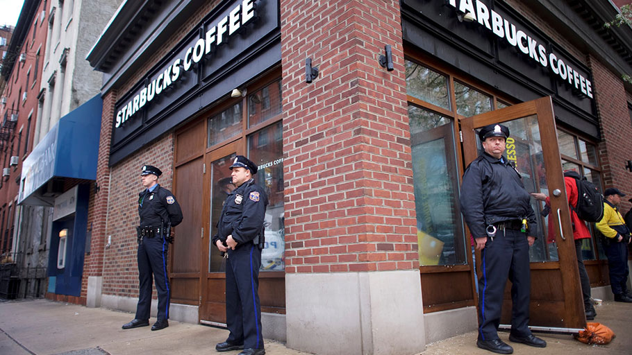 Police officers monitor activity outside as protesters demonstrate inside a Philadelphia Starbucks, where two men were arrested.