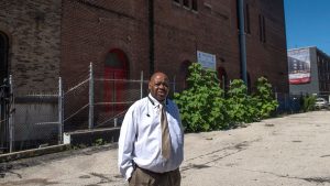 Rev. Robert Johnson stands on the Broad Street next to his church where a New York developer is planning to build $2 million townhouses.