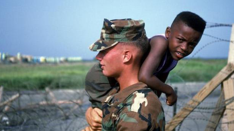 A marine carries a Haitian refugee child at Camp McCalla in Guantánamo Bay in 1992