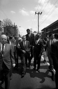 At the funeral of Dr. Martin Luther King Jr., Richard Nixon, surrounded by bodyguards, follows the funeral procession.