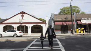 A man and a boy walk across Auburn Avenue on Easter Sunday. On the left is Haugabrooks Funeral Home, established in 1929. Image by Evey Wilson