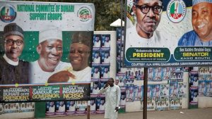 A man takes a call as he stands between two billboards showing Nigeria's President Muhammadu Buhari and other party officials, in Kano, northern Nigeria, February 26, 2019