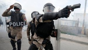 A police officer aims his weapon after demonstrators