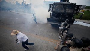 Demonstrators run from a cloud of tear gas