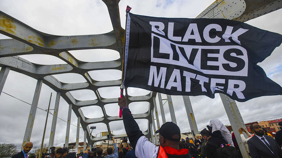 A Black Lives Matter demonstrator waves a flag on the Edmund Pettus Bridge during the Bloody Sunday commemoration in Selma, Alabama, in March.