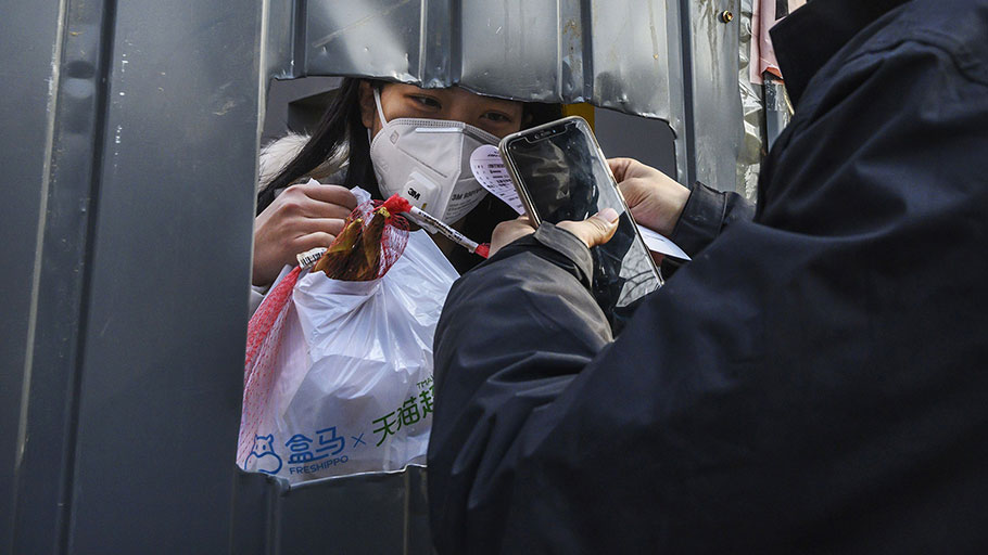 A Chinese woman wears a protective mask as she accepts a package from a courier through a cutout hole on Feb. 25, 2020 in Beijing, China. 