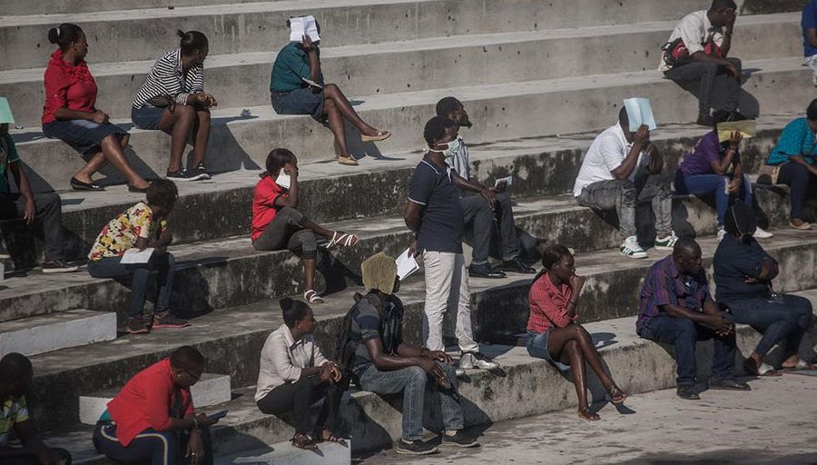 People attempt to social distance as they wait in line in downtown Port-au-Prince on March 26, 2020