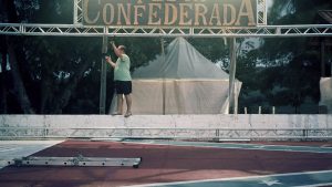 A volunteer helps take down the sign after the 2019 Confederate Festival. The dance floor is emblazoned with a giant Confederate flag.