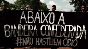 Members and supporters of UNEGRO — United Blacks for Equality — carry a banner that reads, “Down with the Confederate flag” and “#Don’tHoistHate” at the entrance to the 2019 Confederate Festival.