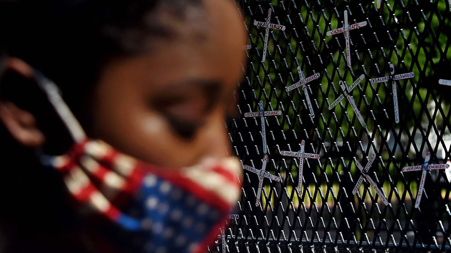 A demonstrator next to a fence bearing names of black people killed by police, Washington DC, June 2020.