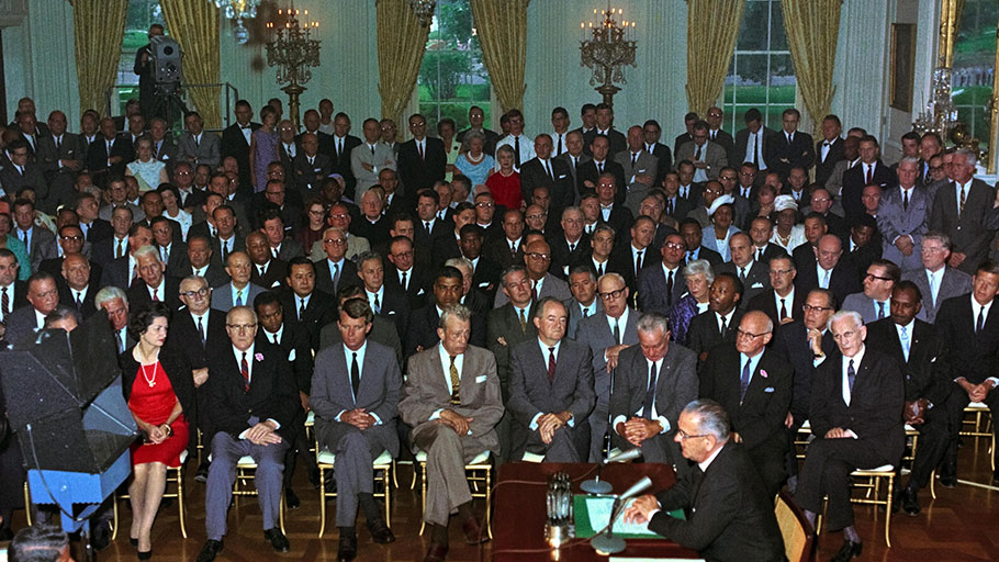 The Civil Rights Act of 1964 being enacted by President Lyndon Johnson.