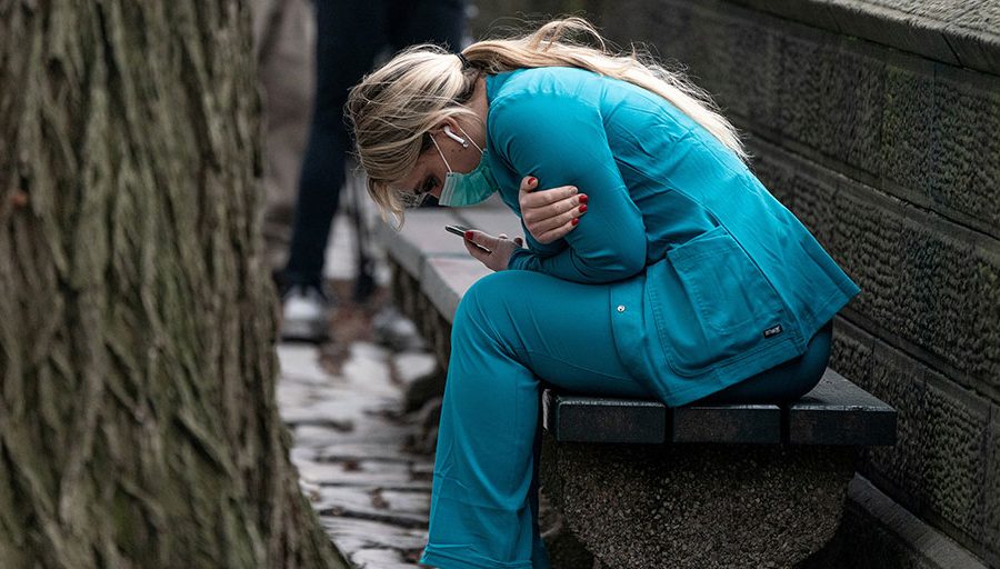 A healthcare worker sits on a bench near Central Park in New York City, on Mar. 30, 2020.