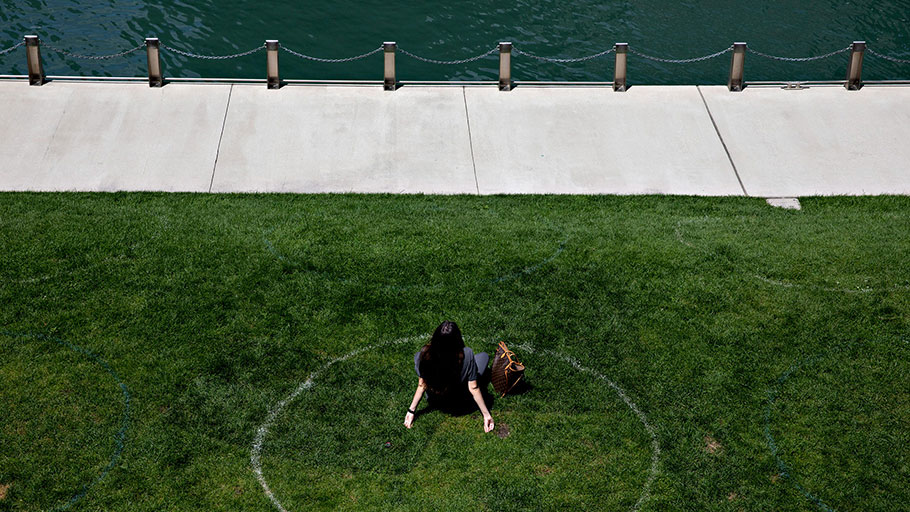 A woman sits in a social distance circle along the Chicago River in Chicago, on Aug. 4, 2020. 
