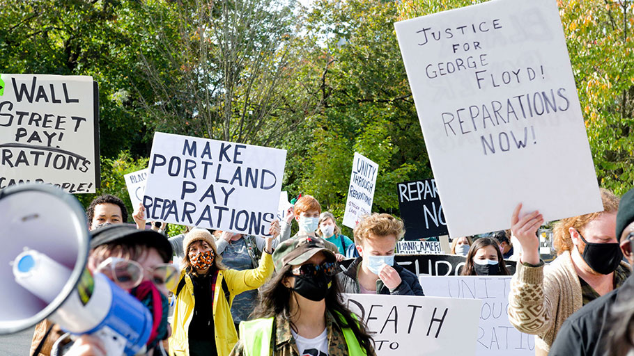 Protesters march with signs calling for reparations and justice for George Floyd.