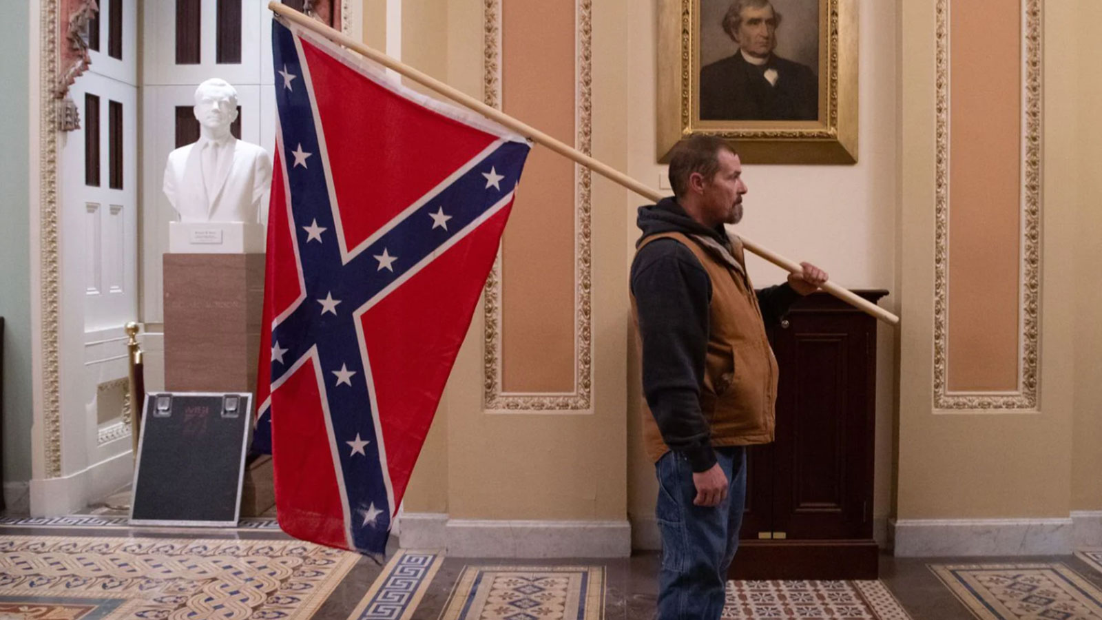A supporter of then-President Donald Trump holds a Confederate battle flag