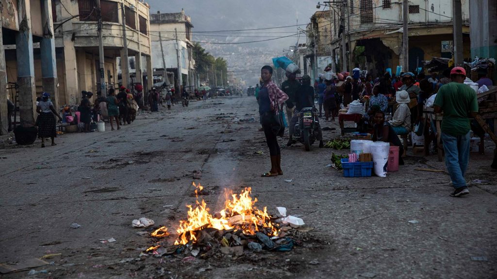 People gather around burning garbage in downtown Port-au-Prince, Haiti.