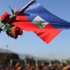 A women holds a Haitian flag and roses