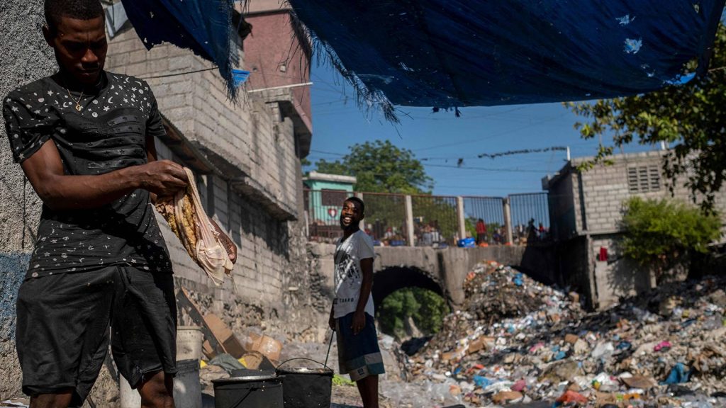 A man cleans meat to cook next to a stream of heavily contaminated water filled with trash in Port-au-Prince, Haiti, on Oct. 29.
