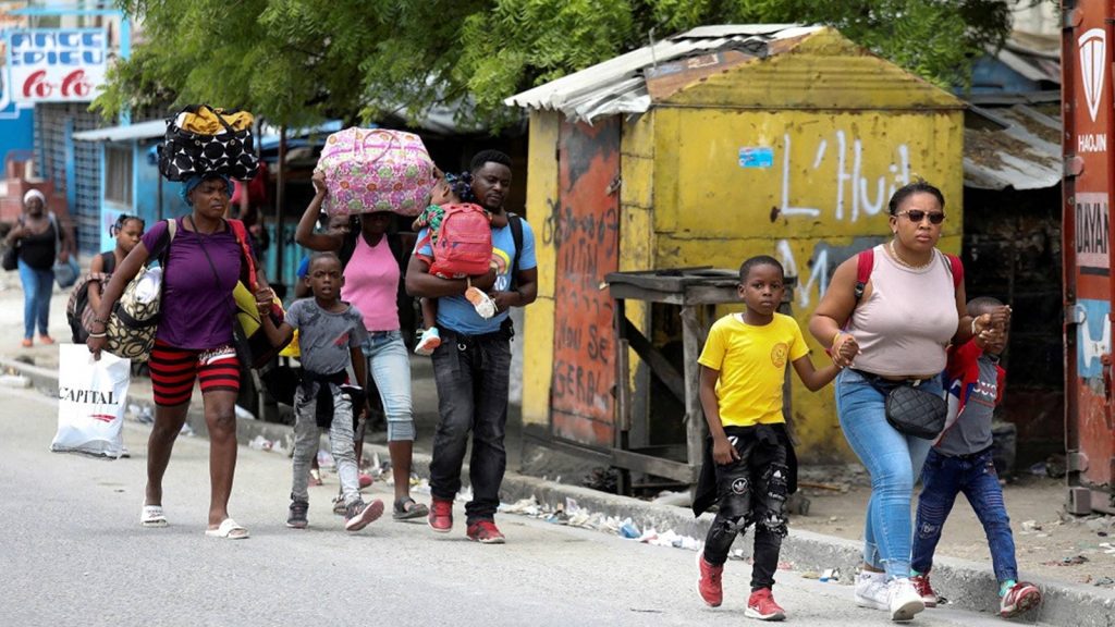 Residents carry their belongings as they flee their homes due to ongoing gun battles between rival gangs, in Port-au-Prince on May 2, 2022