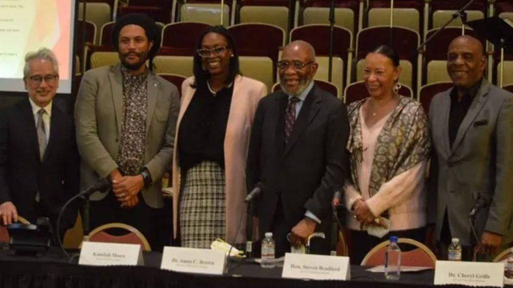 Six of the nine members of the California Task Force to Study and Develop Reparations Proposals for African Americans. From left to right are Don Tamaki, Jovan Scott Lewis, chair Kamilah Moore, vice-chair Dr. Rev. Amos Brown, Dr. Cheryl Grills, and California State Sen. Steven Bradford (D-Gardena).