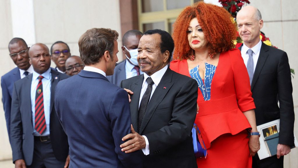 Cameroonian President Paul Biya shakes hands with French President Emmanuel Macron as Biya's wife, Chantal, looks on, after their meeting at the presidential palace, in Yaounde, Cameroon, on July 26.
