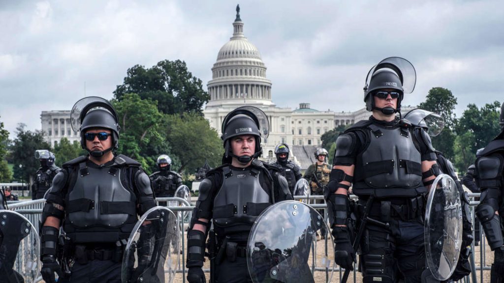 Police officers in riot gear stand guard in front of the U.S. Capitol where a rally is held to defend supporters of former president Donald Trump who were arrested for storming the Capitol on January 6, 2021