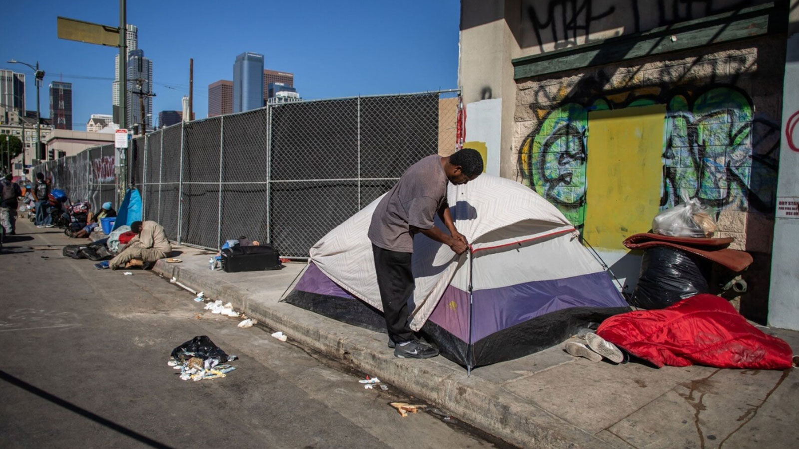 A homeless man zips up his tent in front of the nonprofit Midnight Mission's headquarters in the Skid Row neighborhood of downtown Los Angeles in 2021.