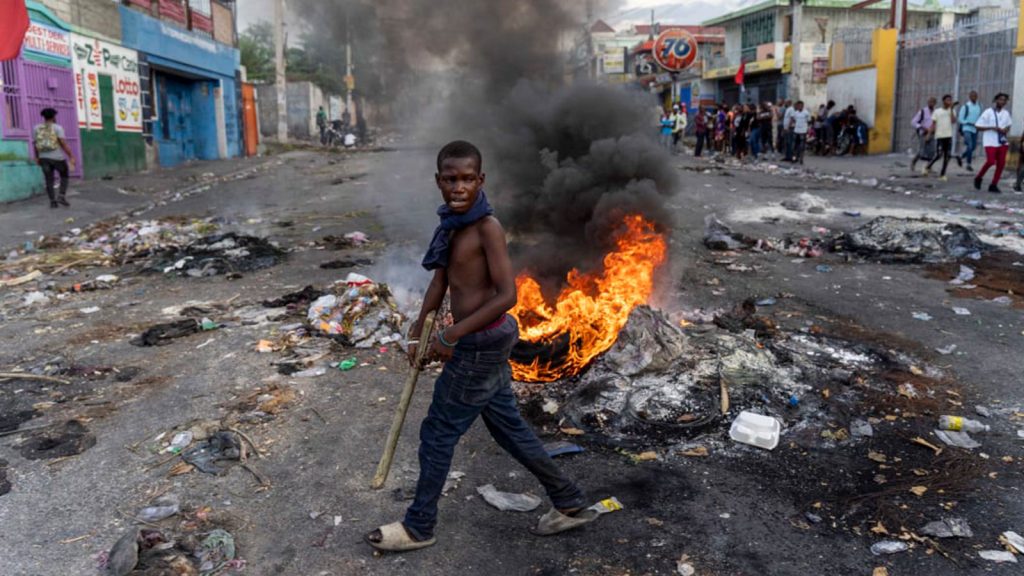 A young man walks past a burning barricade during a protest against Haitian Prime Minister Ariel Henry, calling for his resignation, in Port-au-Prince.