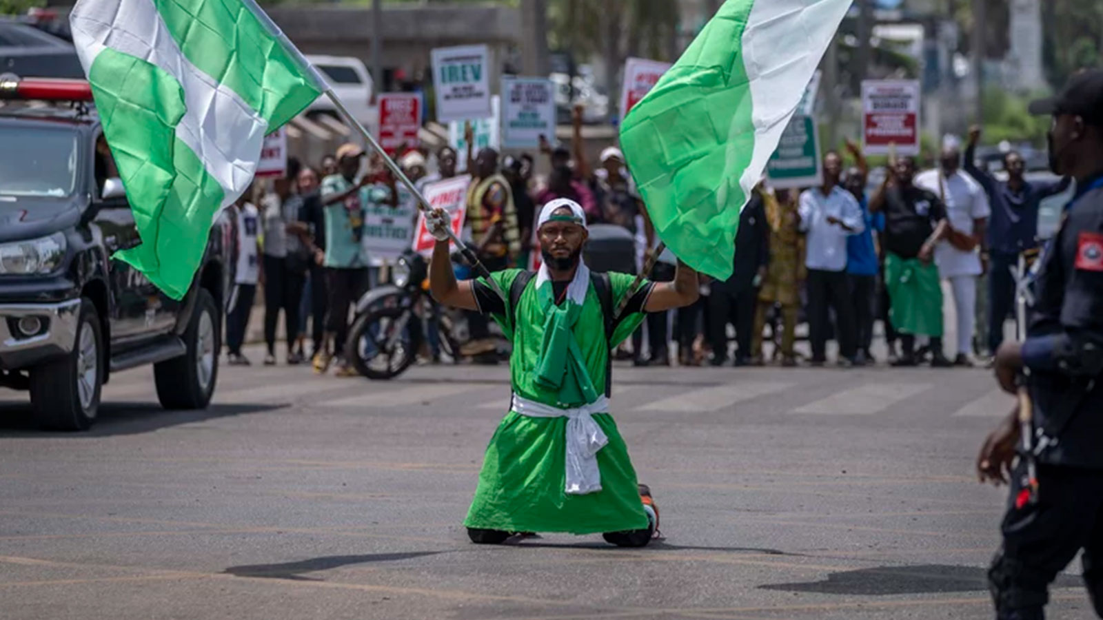 A demonstrator holds two Nigerian flags as he and others accusing the election commission of irregularities and disenfranchising voters make a protest in downtown Abuja, Nigeria.