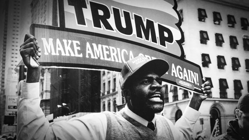 Black Trump supporter holding MAGA sign