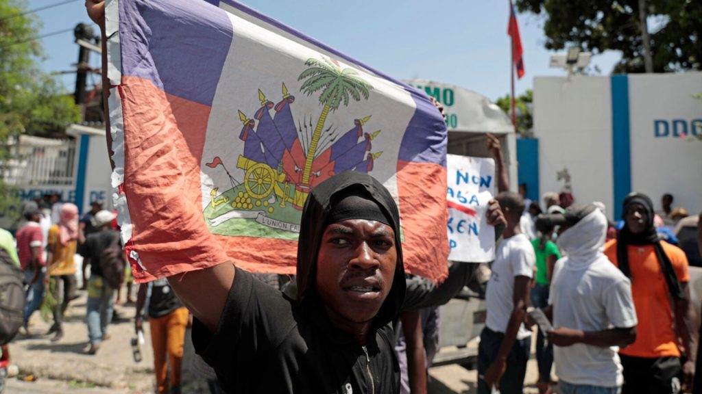 A demonstrator holds up a Haitian flag at a protest of insecurity in Port-au-Prince on Aug. 7. Armed gangs control large sections of the capital and are spreading into the countryside.