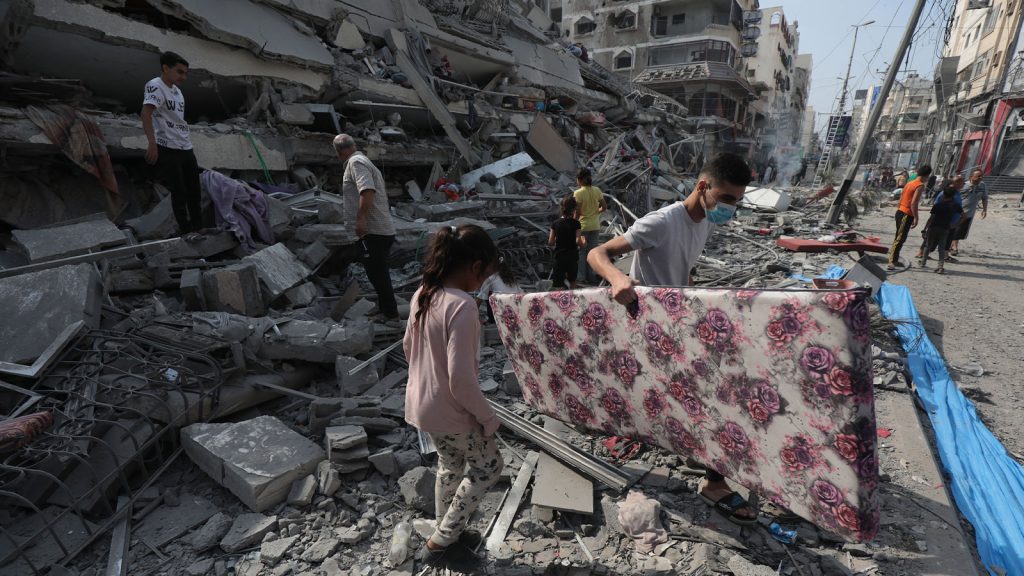 Palestinians inspect the ruins of Aklouk Tower destroyed in Israeli airstrikes in Gaza City on October 8, 2023.