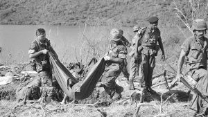 Members of the U.S. Army graves registration team carry a body bag containing the remains of the one of three to four bodies fond in a shallow grave at the Calivigny, Grenada, military training compound on Nov. 8, 1983.