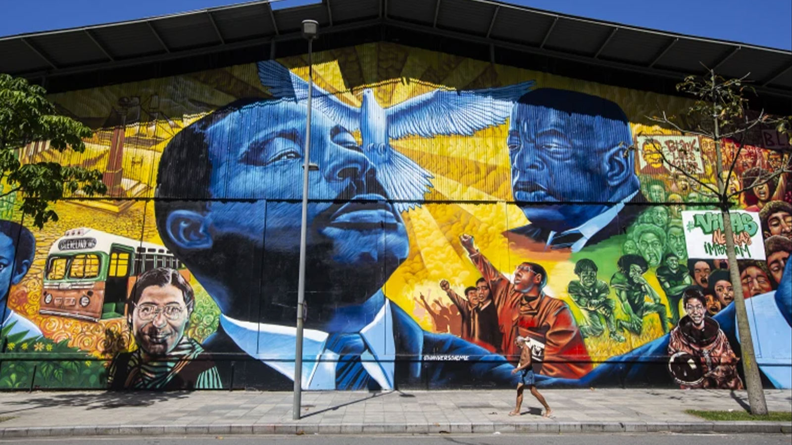 A pedestrian walks past the Sonhos de Liberdade mural created by artist Acme, which honors leaders in the fight for racial equality, in the Porto art district of Rio de Janeiro, Brazil, Nov. 17, 2021. 