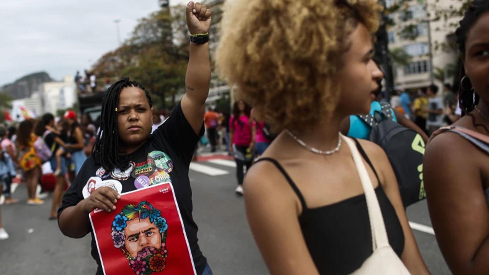 A woman raises her fist while holding a sign with a visage of then former President Luiz Inacio Lula da Silva during a Black Women’s March in Rio de Janeiro, Brazil, July 31, 2022.