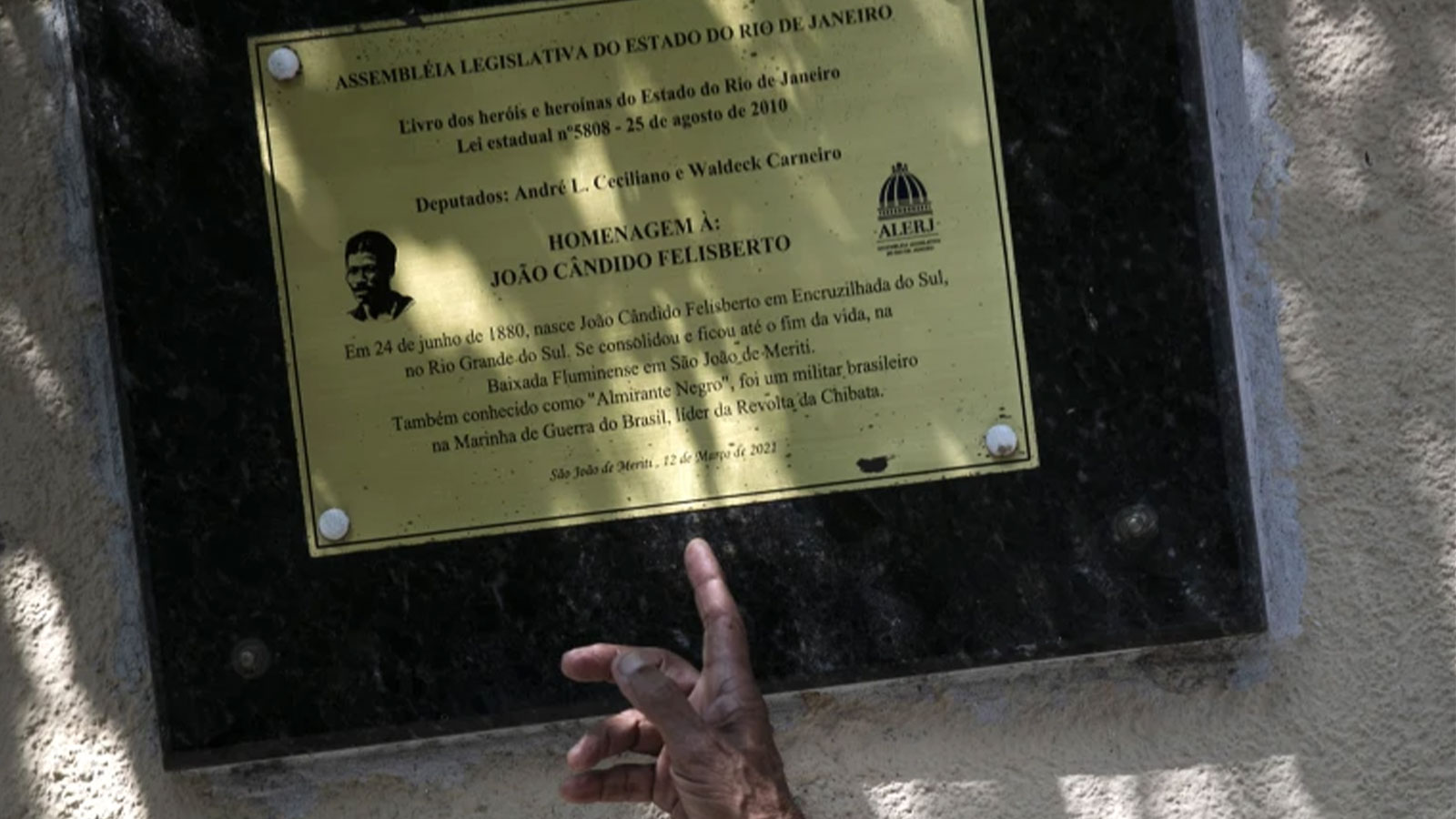 Adalberto Cândido points to a memorial plaque honoring his father João Cândido, a black sailor who led a revolt against against regular whipping by the Brazilian naval officers in 1910, in Sao Joao de Meriti, Rio de Janeiro state, Brazil, Thursday, Dec. 21, 2023.