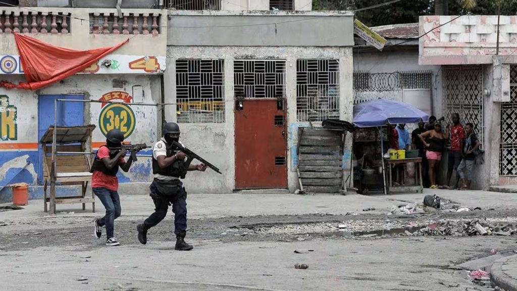 People huddle in a corner as police patrol the streets after gang members tried to attack a police station, in Port-au-Prince, Haiti April 25, 2023.
