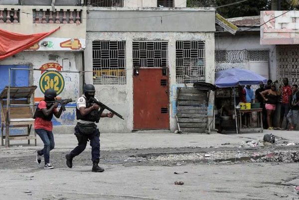 People huddle in a corner as police patrol the streets after gang members tried to attack a police station, in Port-au-Prince, Haiti April 25, 2023.