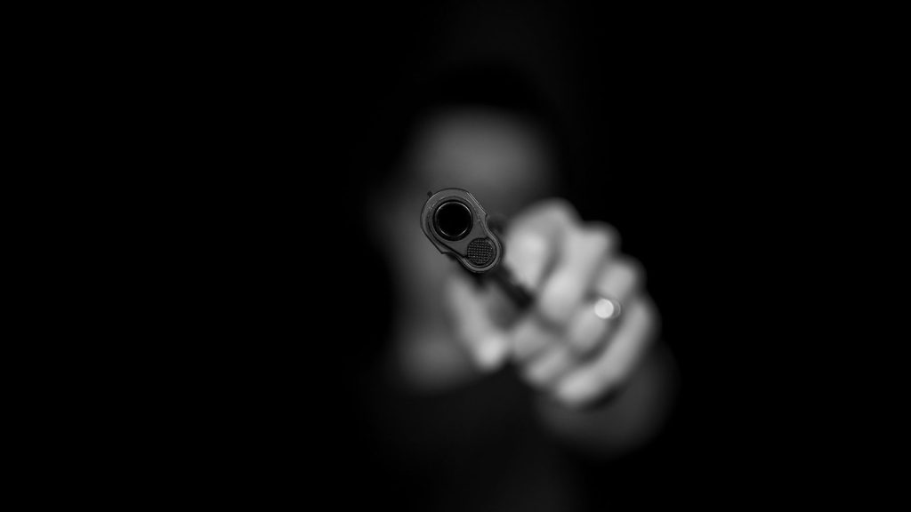 Man holding gun. Photo by Max Kleinen on Unsplash